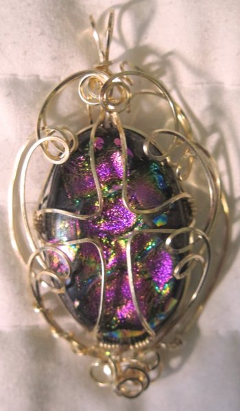 Fused dichroic glass cabochon in gold filled wire setting.